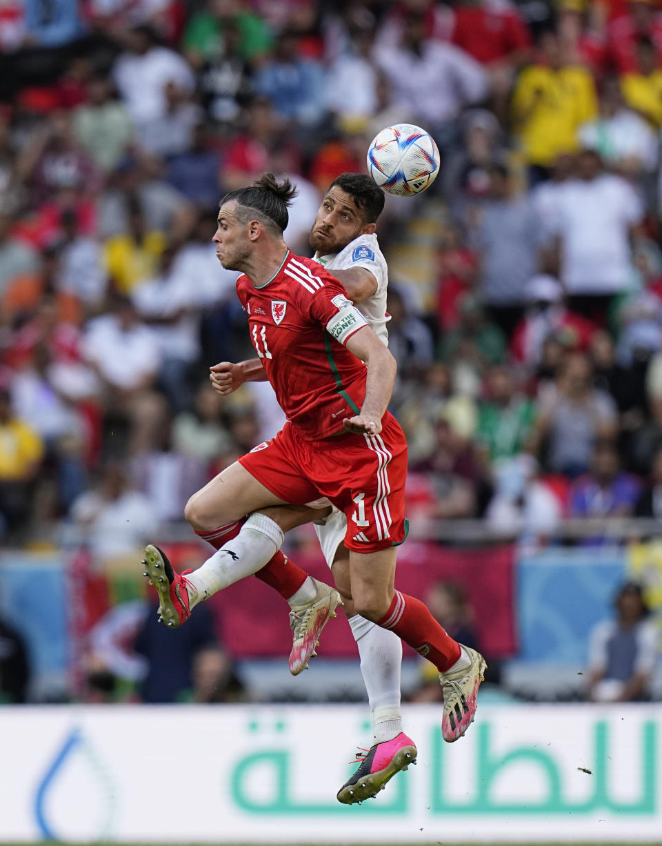 Gareth Bale (derecha) salta por el balón con el iraní Morteza Pouraliganji durante el partido del Grupo B del Mundial entre Gales e Irán, en el estadio Ahmad Bin Ali en Rayán , Qatar, el 25 de noviembre de 2022. (AP Foto/Pavel Golovkin)