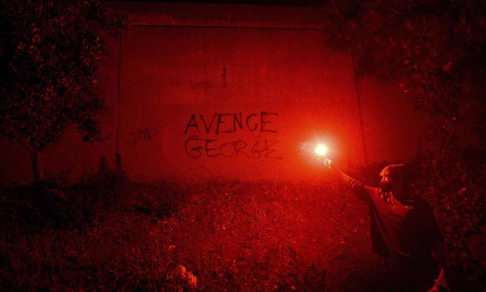 In this May 29, 2020, photo, a demonstrator holds a flare in Oakland, Calif. while protesting the Monday death of George Floyd, a handcuffed black man in police custody in Minneapolis. (AP Photo/Noah Berger)