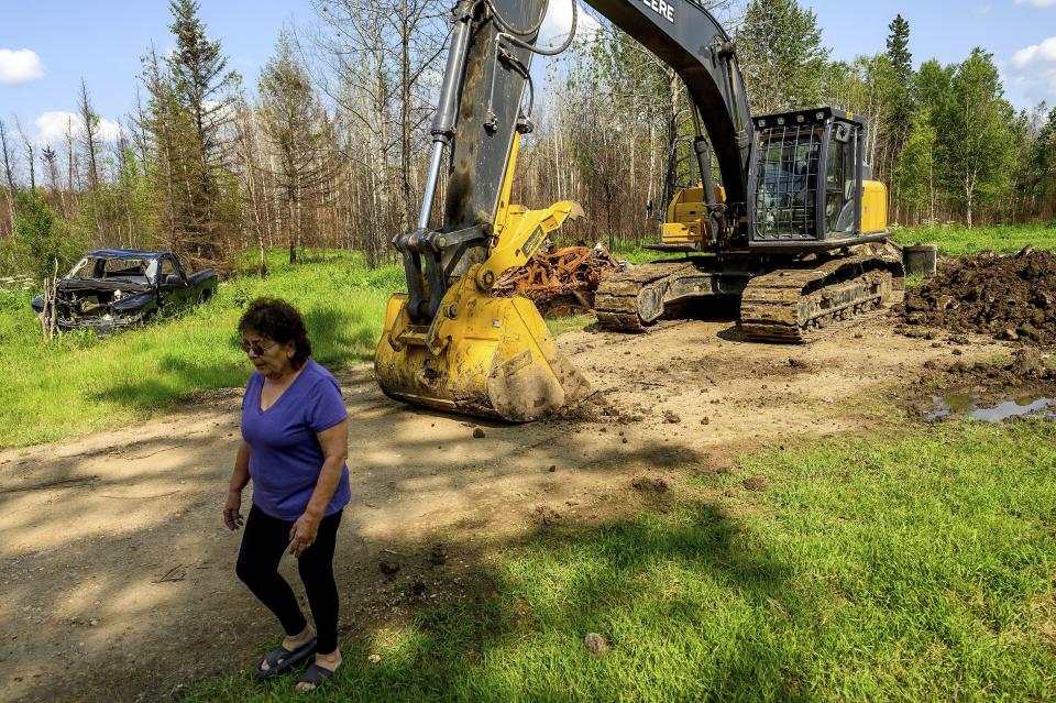 Carrol Johnston, who lost her home in a May wildfire, walks through her property in the East Prairie Metis Settlement, Alberta, on Wednesday, July 4, 2023. Johnston, who has been living in a nearby town, is awaiting a modular home so she can return to the land. (AP Photo/Noah Berger)