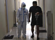 Dr. Irman Pahlepi, left, talks with a COVID-19 patient at the Dr. Suyoto General Hospital in Jakarta, Indonesia, on July 29, 2021. Pahlepi is back at work in the hospital, immediately resuming his duties treating COVID-19 patients after recovering from an infection himself, for the second time. With numbers of infections in Indonesia skyrocketing and deaths steadily climbing, health care workers are being depleted as the virus spares nobody, Pahlepi felt he had no option but to jump right back in. (AP Photo/Tatan Syuflana)