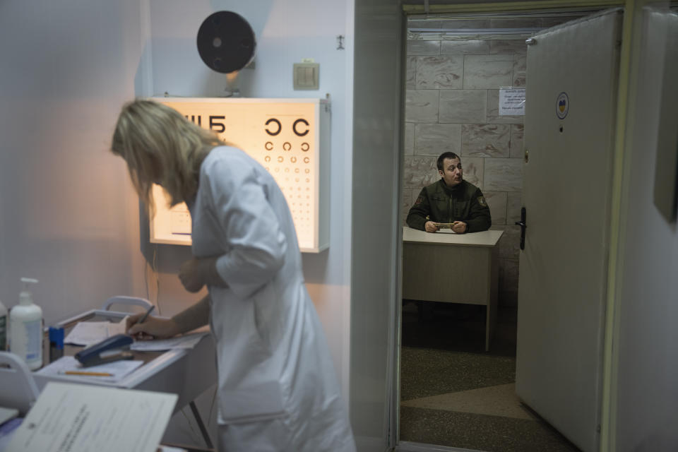 An ophthalmologist looks through her papers during medical examination of recruits in a city hospital in Kyiv, Ukraine, Thursday, Feb. 8, 2024. As the third year of war begins, the most sensitive and urgent challenge pressing on Ukraine is whether it can muster enough new soldiers to repel – and eventually drive out – an enemy with far more fighters at its disposal. (AP Photo/Efrem Lukatsky)