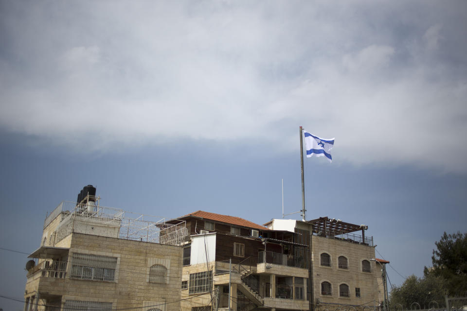 In this March 13, 2019 photo, an Israeli flag flies on a building in east Jerusalem's Mount of Olives. The Falic family, owners of the ubiquitous chain of Duty Free America shops, fund a generous, and sometimes controversial, philanthropic empire in Israel that stretches deep into the West Bank. The family supports many mainstream causes as well as far right causes considered extreme even in Israel. (AP Photo/Ariel Schalit)