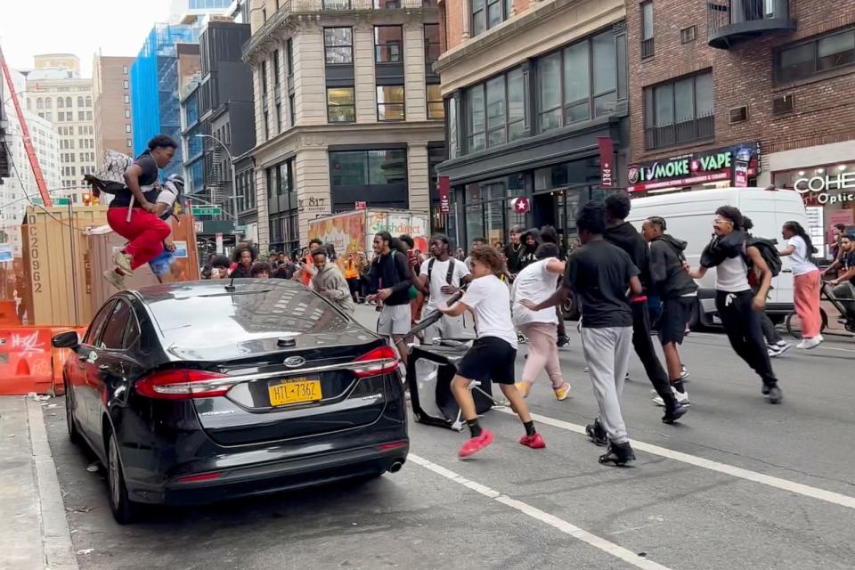 PHOTO: A man jumps on a car as a crowd runs through the street on Broadway near Union Square, Aug. 4, 2023, in New York. (Bobby Calvan/AP)