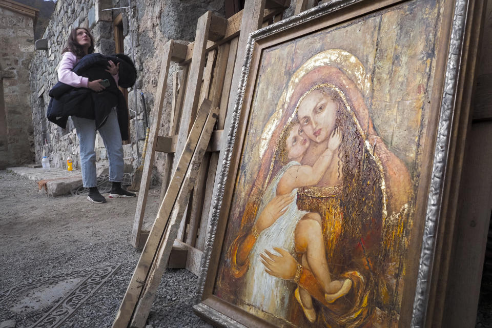 A woman holds her baby covered with her coat next to an icon at the Dadivank, an Armenian Apostolic Church monastery dating to the 9th century, as ethnic Armenians leave the separatist region of Nagorno-Karabakh to Armenia, Saturday, Nov. 14, 2020. The territory is to be turned over to Azerbaijan on Sunday as part of territorial concessions in an agreement to end six weeks of intense fighting with Armenian forces. Hundreds of thousands of Azeris were displaced by the war that ended in 1994. It is unclear when any civilians might try to settle in Karvachar — which will now be known by its Azeri name Kalbajar — or elsewhere. (AP Photo/Dmitry Lovetsky)