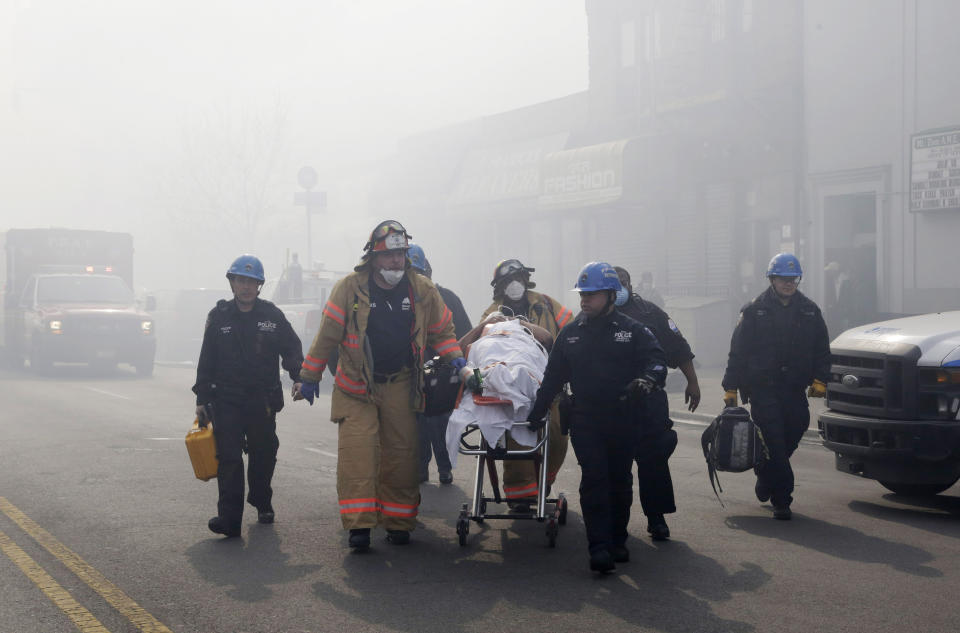 Rescue workers remove an injured person on a stretcher following a building explosion and collapse in East Harlem, Wednesday, March 12, 2014 in New York. (AP Photo/Mark Lennihan)