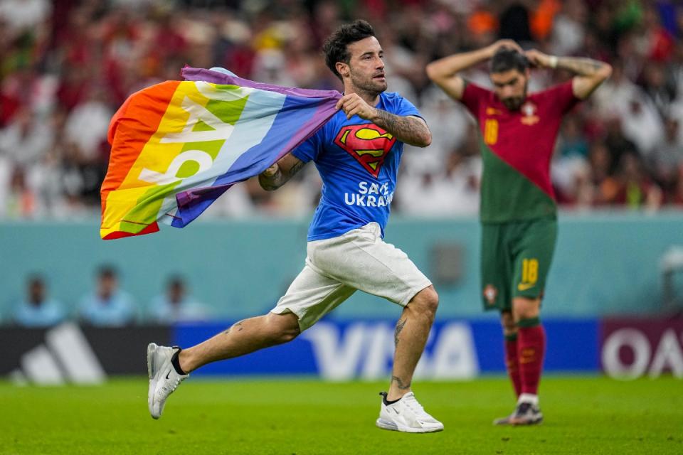 A pitch invader runs across the field with a rainbow flag during the World Cup group H football match between Portugal and Uruguay, at the Lusail Stadium in Lusail, Qatar, Monday, Nov. 28, 2022. (AP Photo/Abbie Parr)