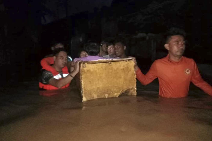 In this photo provided by the Philippine Coast Guard, rescuers use a makeshift float as they evacuate residents from flood waters caused by Tropical Storm Nalgae in Zamboanga, southern Philippines on Saturday Oct. 29, 2022. Flash floods and landslides set off by torrential rains left dozens of people dead, including in a hard-hit southern Philippine province, where many villagers are feared missing and buried in a deluge of rainwater, mud, rocks and trees, officials said Saturday. (Philippine Coast Guard via AP)