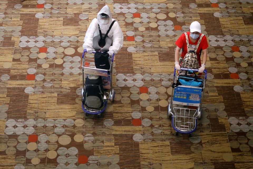 A person wearing a protective gear walks next to someone wearing a face mask and gloves at Changi Airport in Singapore on 30 March, 2020. (PHOTO: Reuters)