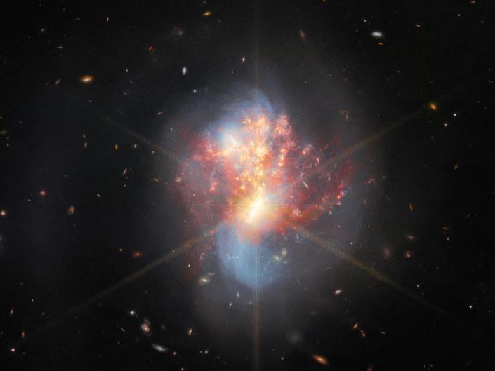 bright colorful oval of two galaxies merging together red orange blue yellow in deep space