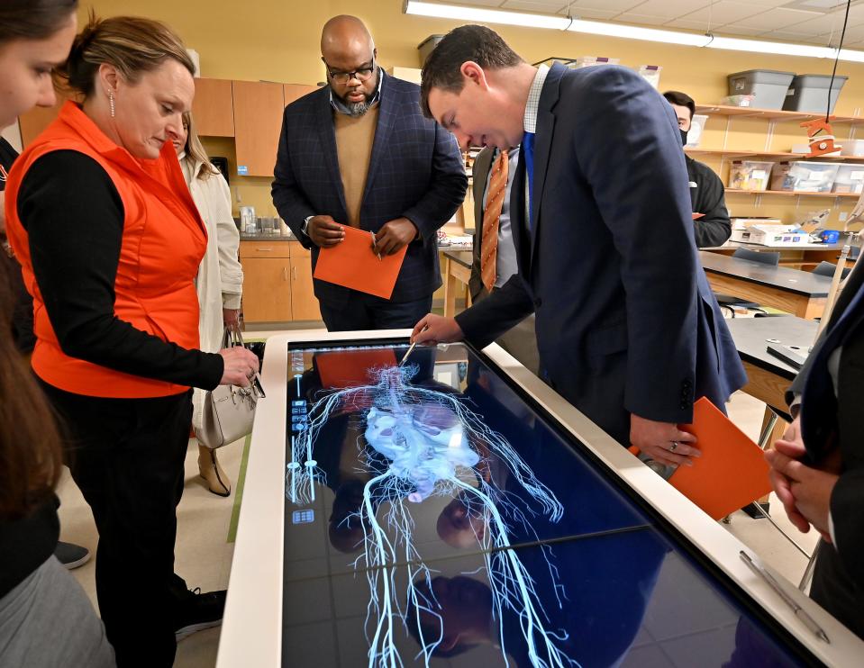 State Secretary of Education Patrick Tutwiler, center, watches as Uxbridge High School Science Department teacher Tracy Larkin guides state Sen. Ryan Fattman through the biomedical science class's virtual cadaver during their visit to the school Friday.