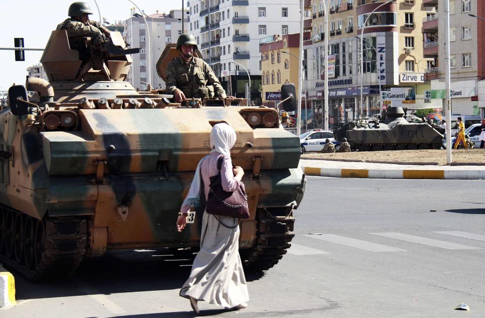 A woman walks past a tank from which Turkish soldiers keep guard on a main street in Diyarbakir October 8, 2014. At least 12 people died on Tuesday during violent clashes across Turkey, local media reported, as the fate of the besieged Syrian border town of Kobani stirred up decades of tensions with Turkey's Kurdish minority. Violence erupted in Turkish towns and cities mainly in the Kurdish southeastern provinces, as protesters took to the streets to demand the government do more to protect Kobani, a predominantly Kurdish settlement which has been surrounded by Islamic State fighters for three weeks. REUTERS/Sertac Kayar (TURKEY - Tags: POLITICS CIVIL UNREST MILITARY)