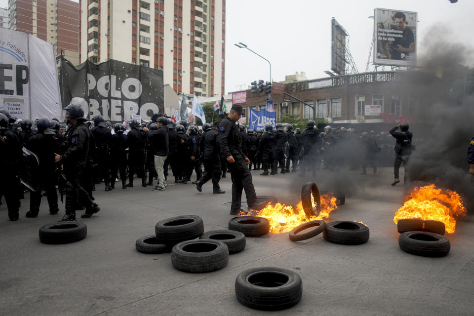 Un oficial de policía intenta apagar las llamas de los neumáticos incendiados por manifestantes antigubernamentales que protestan por la escasez de alimentos en los comedores populares y las reformas económicas propuestas por el presidente Javier Milei en Buenos Aires, Argentina, el martes 7 de mayo de 2024. (AP Foto/Natacha Pisarenko)