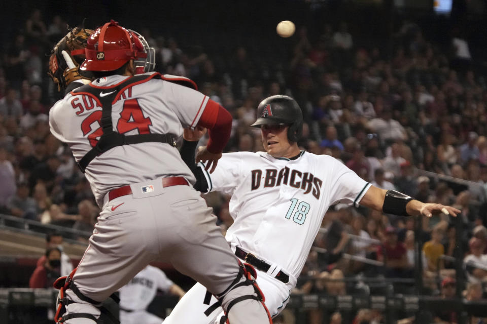 Arizona Diamondbacks' Carson Kelly (18) scores under the tag of Los Angeles Angels catcher Kurt Suzuki during the sixth inning of a baseball game Friday, June 11, 2021, in Phoenix. (AP Photo/Rick Scuteri)