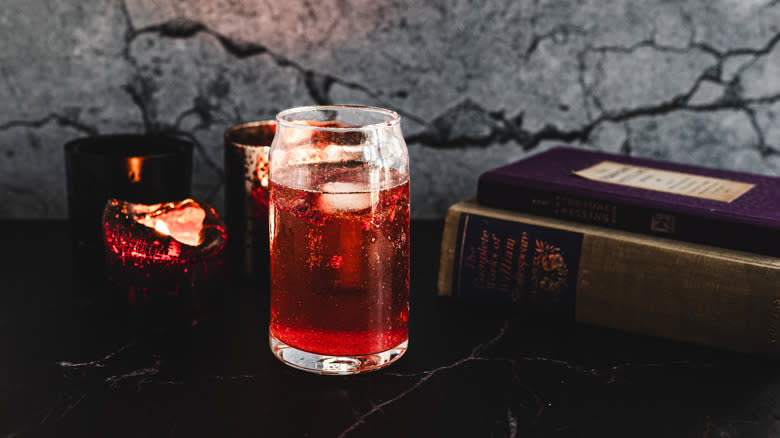 Red cocktail glass in front of books and candles