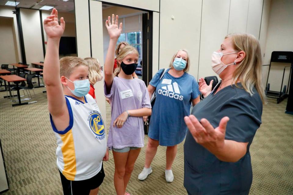 “Who wants to go first?” Pam Scott, RN, right, asks 12-year-old triplets Eli Strickland, left, Campbell Strickland, center, and Emma Strickland, back left, during the WakeMed Back-to-School Blitz vaccine clinic at the WakeMed Raleigh Campus in Raleigh, N.C., Sunday, August 1, 2021. Mom Bridget Strickland, center right, watches. Emma Strickland was the first of the three to get her shot.