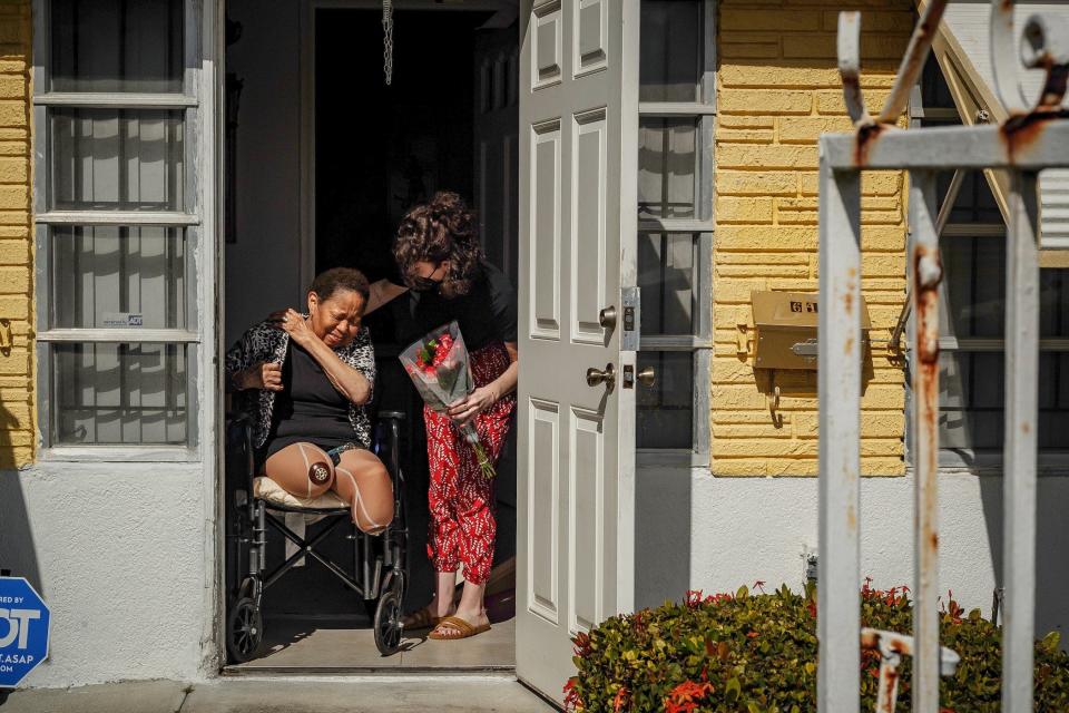 71-year-old Linda Morris is greeted with flowers by Chelsea Ellinger, Boynton Beach, at her home in Riviera Beach.