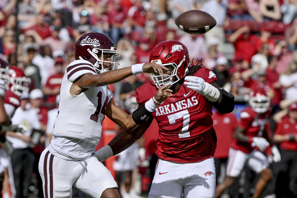 Mississippi State quarterback Mike Wright (14) throws a pass as Arkansas defensive lineman Trajan Jeffcoat (7) puts on the pressure during the first half of an NCAA college football game Saturday, Oct. 21, 2023, in Fayetteville, Ark. (AP Photo/Michael Woods)