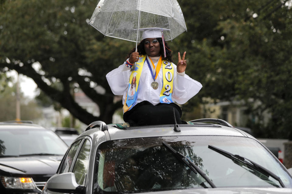 Graduates of New Orleans Charter Science and Math High School class of 2020 parade in vehicles after holding a drive-in graduation ceremony as a result of the COVID-19 pandemic, outside Delgado Community College in New Orleans, Wednesday, May 27, 2020. Students and family got out of their cars to receive diplomas one by one, and then held a parade of cars through city streets. (AP Photo/Gerald Herbert)