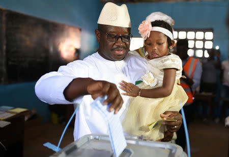 Julius Maada Bio, the presidential candidate for the Sierra Leone People's Party (SLPP), carries his daughter as he casts his vote during Sierra Leone's general election in Freetown, Sierra Leone March 7, 2018. REUTERS/Olivia Acland