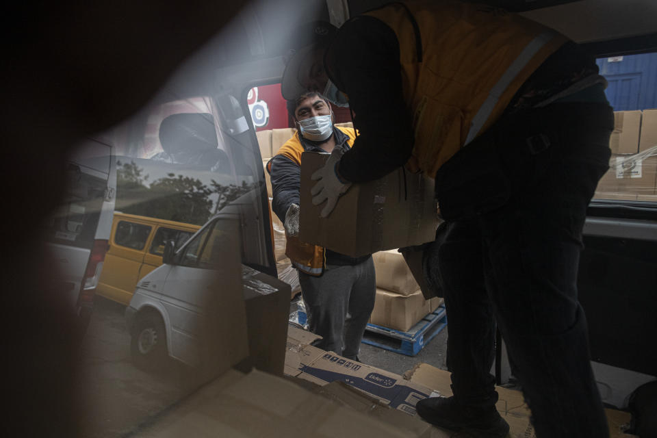 City workers load food kits into a van to be delivered to residents affected economically by the disruptions of the new coronavirus pandemic, in Santiago, Chile, Thursday, March 18, 2021. Fresh outbreaks of COVID-19 have led to renewed lockdowns throughout the country. (AP Photo/Esteban Felix)