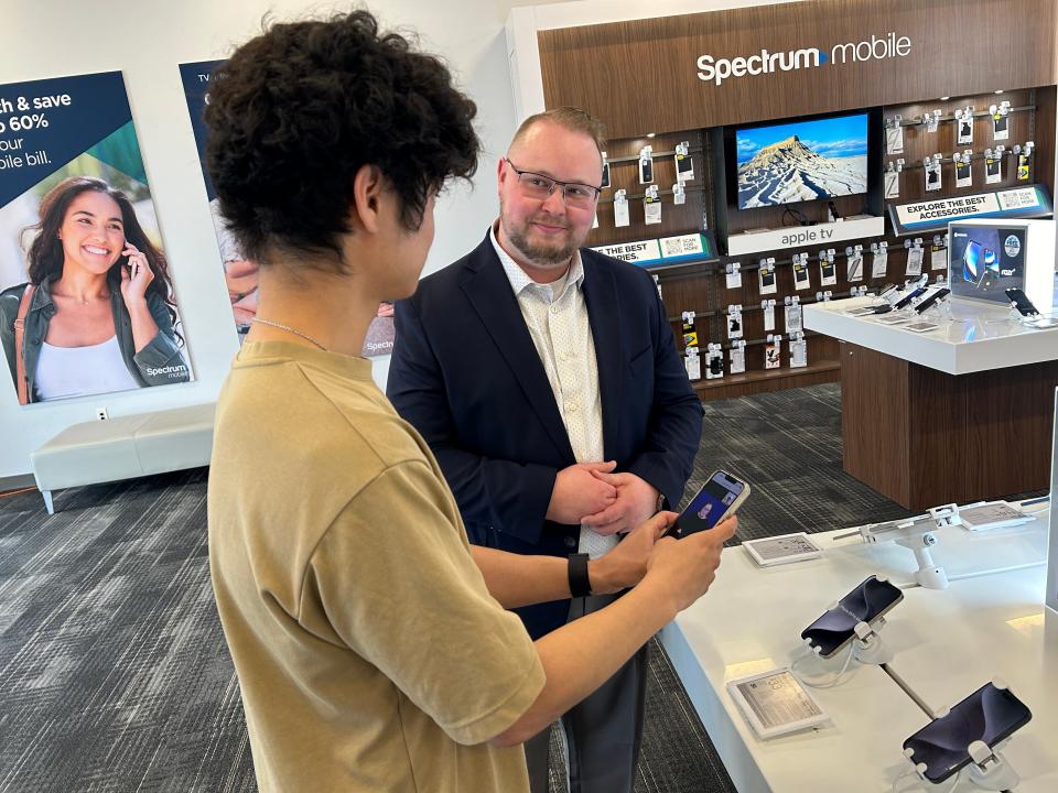 Trent Gobble, left, tries out Charter Communications/Spectrum's pilot ASL Video Relay Service Interpreter program alongside the Henrietta store's territory manager Josh Berbs in April 2024. The program aims to ease communication between the deaf community and Spectrum employees.