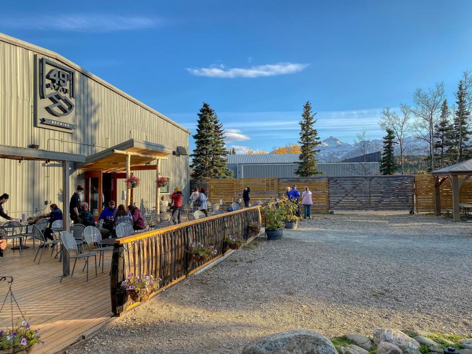 Beige metal exterior of a busy brewery in Alaska with a mountain view