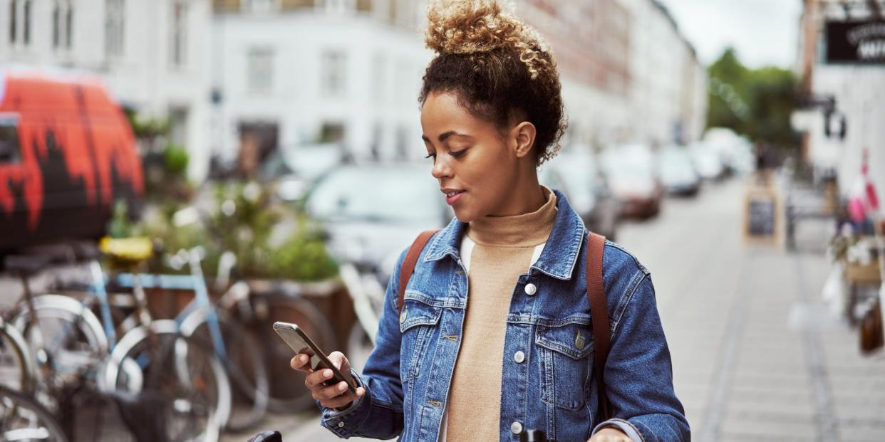 woman with bike holding phone walking in city