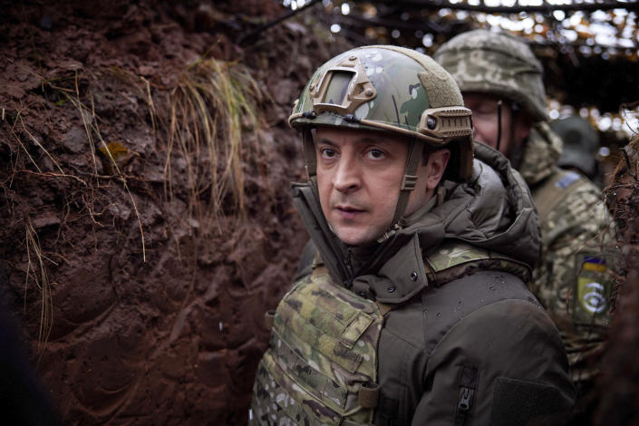 FILE - Ukrainian President Volodymyr Zelenskyy walks under a camouflage net in a trench as he visits the war-hit Donetsk region in eastern Ukraine, Dec. 6, 2021. Zelenskyy praised Ukraine’s soldiers on a visit to an area near the conflict zone to mark a military holiday. (Ukrainian Presidential Press Office via AP, File)