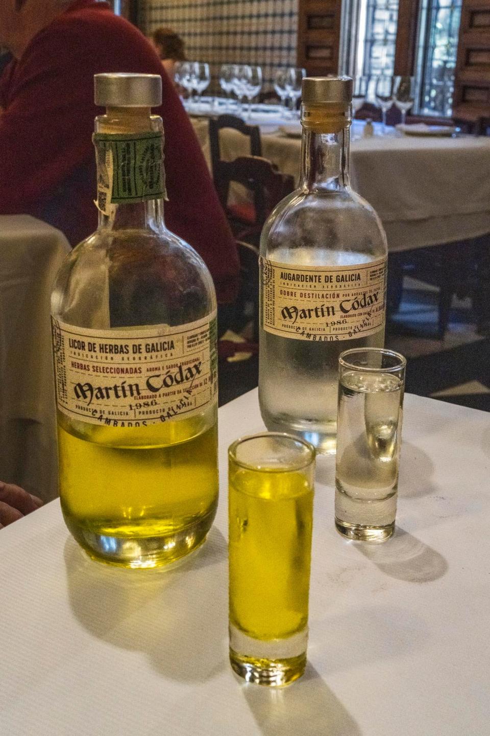 Two bottles and two small glasses of alcohol on a table.