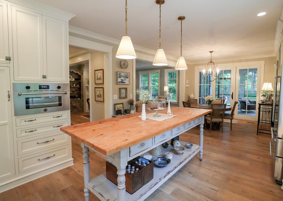 The kitchen in the home of Tracee Dore.  She describes it like this: Danby Marble counter tops.  Cabinetry is designed to look as if it were built in a hundred years ago with the unusual latches, baseboard and furniture look.  The island it the major statement piece and anchors the room with its rustic yet refined finish.  Great for our family, as it shows no wear and tear.  My favorite thing about the kitchen is my signature design of using lots of windows.  The more light the better and we love being able to look out of the home and see the beautiful yard at every angle.  The large kitchen window faces the "friendrance", so its always nice to see guests coming and be able to greet them before they get to the door.  