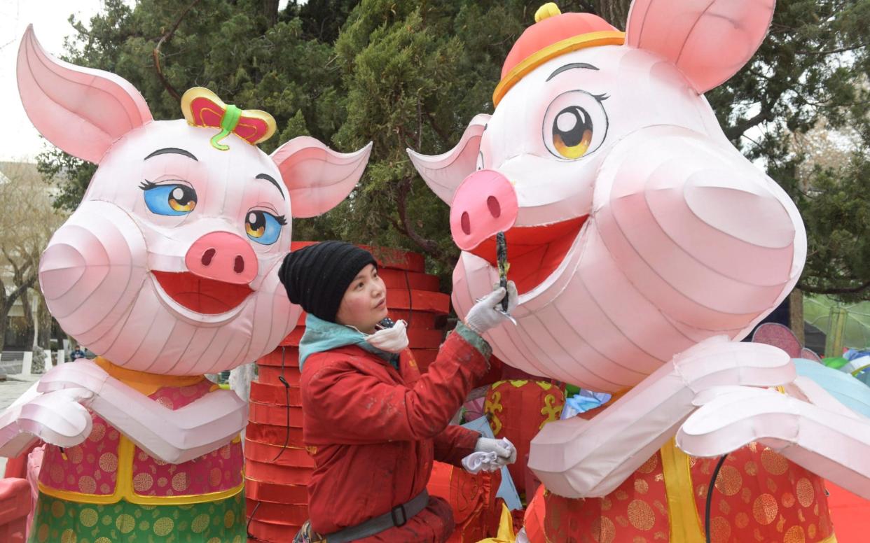 A craftswoman paints a lantern in the shape of a pig in Jinan, China, on January 9, 2019 - Visual China Group
