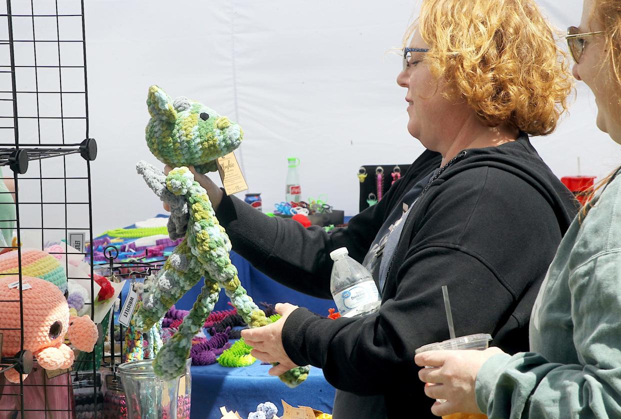 Stacy Carter looks at a plush toy for her nephew during the Sunflower Market at Lambrecht Farm on Saturday, May 11, 2024. The event attracts many craft vendors, and there was also live music, a petting zoo, and plenty of food trucks.