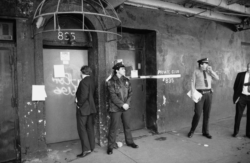 FILE - In this Nov. 7, 1985 file photo, police stand outside the Mine Shaft, a gay bar which was shut down in Greenwich Village, New York. It was the first move by the city against premises that allegedly permit "high-risk" sexual activity that can spread the AIDS disease. (AP Photo/Rich Maiman, File)