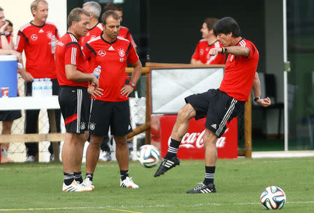 Germany's national soccer team coach Joachim Loew kicks a ball as assistant coach Hansi Flick (C) and goalkeeper coach Andreas Koepke look on during a training session in the village of Santo Andre north of Porto Seguro July 10, 2014. REUTERS/Arnd Wiegmann