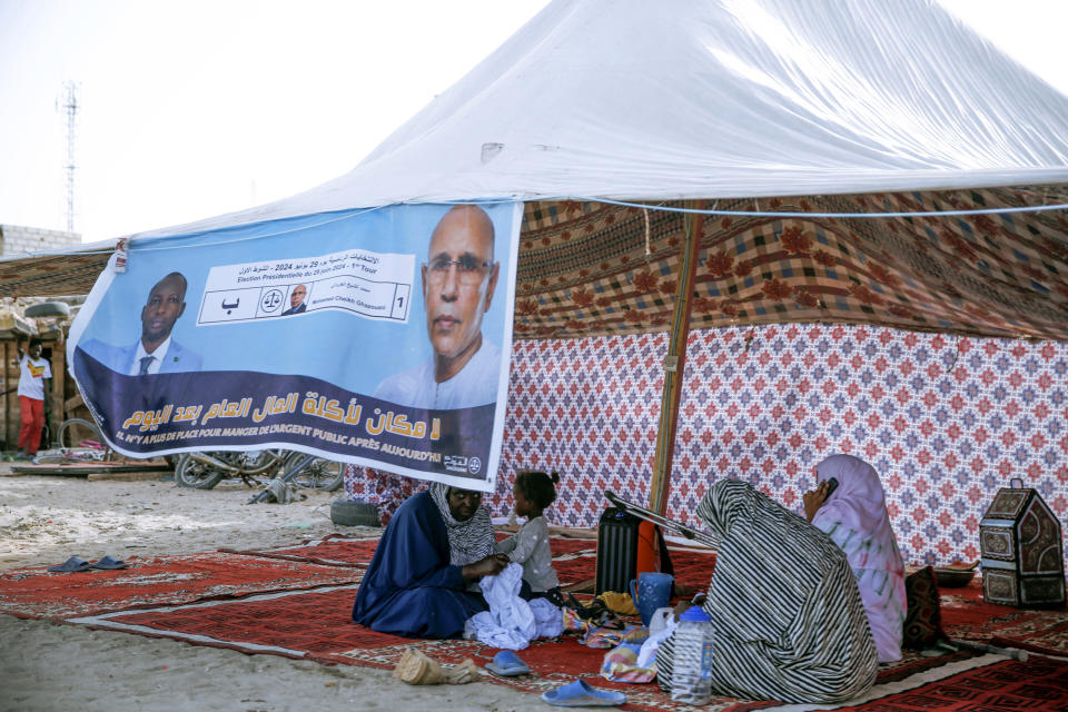 Women sit behind an electoral banner for Mauritanian president Mohamed Ould Ghazouani, during a campaign rally ahead of the presidential elections in Nouakchott, Mauritania, Wednesday, June 26, 2024. The banner reads: "There is no place for people embezzling public funds anymore." (AP Photo/Mamsy Elkeihel)