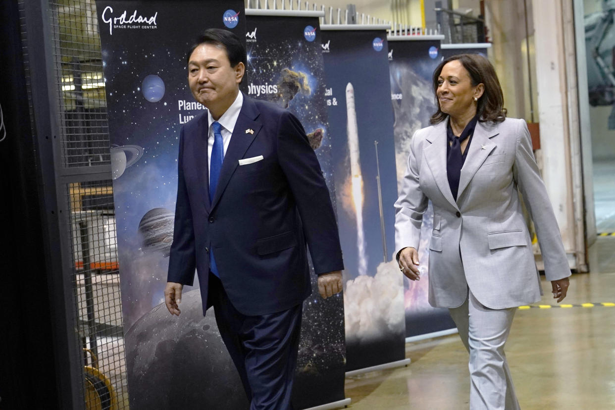 South Korea's President Yoon Suk Yeol and Vice President Kamala Harris pass four panels marked Goddard showing images of planets and successful NASA launches.