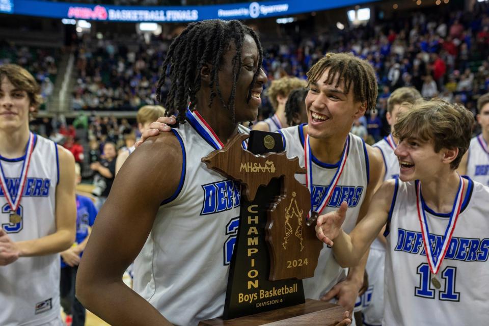 Wyoming Tri-unity Christian's Akais Giplaye (20) celebrates with his teammates Trey Rillema (14) and Chris Boileau (11) after defeating Mt. Pleasant Sacred Heart during the MHSAA Div. 4 state finals at the Breslin Center in East Lansing on March 16, 2024.