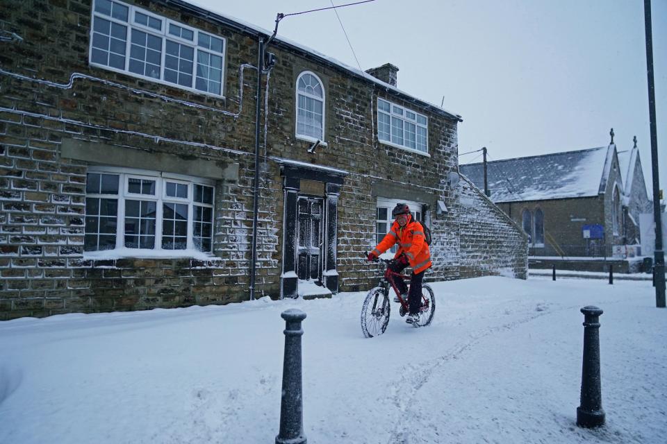 A cyclist makes their way through the snow in Tow Law, Co Durham, after heavy overnight snow fall (PA)