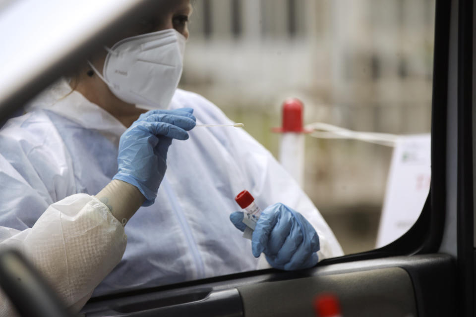 A medical worker wearing protective gear takes swabs to test for COVID-19 at a drive-through for people returning from Croatia, Spain, Malta and Greece, at the San Carlo hospital, in Milan, Italy, Tuesday, Aug. 25, 2020. People returning to Italy from Spain, Malta, Greece and Croatia must be tested within 48 hours of entering the country, after those nations saw worrisome upticks in infections. (AP Photo/Luca Bruno)