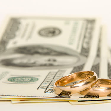 Gold-wedding-bands-stacked-on-money_web