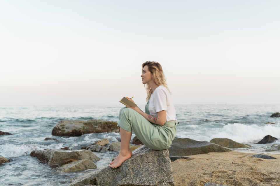 Woman journaling by the ocean