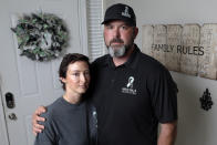 In this Oct. 12, 2021, photo, David and Wendy Mills, parents of Kailee Mills who was killed four years ago in an automobile accident when riding in the back seat without a seat belt, with a photo of their daughter at their home in Spring, Texas. The teenager was riding in the back seat of a car to a Halloween party in 2017 just a mile from her house when she unfastened her seat belt to slide next to her friend and take a selfie. Moments later, the driver veered off the road and the car flipped, ejecting her. (AP Photo/Michael Wyke)