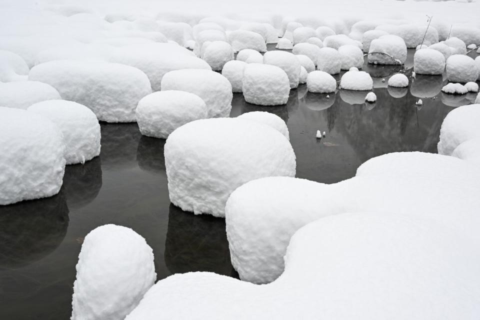 Snow blankets rocks along the river inside Yosemite National Park.