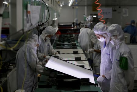 Employees work on the production line of a television factory under Zhaochi Group in Shenzhen