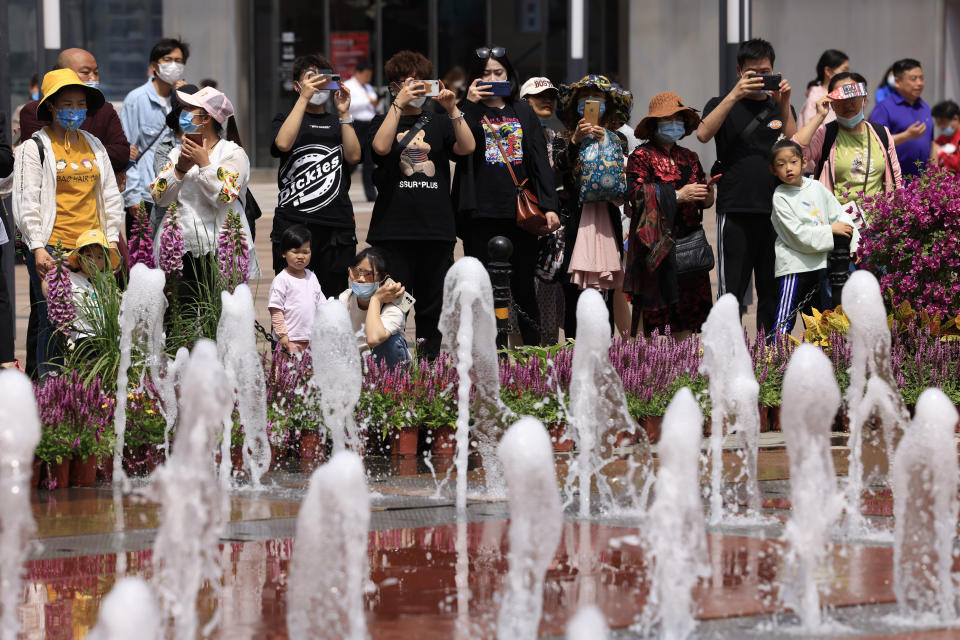 Residents watch a fountain show along the Wangfujing shopping district in Beijing Tuesday, May 11, 2021. The number of working-age people in China fell over the past decade as its aging population barely grew, a census showed Tuesday, adding to economic challenges for Chinese leaders who have ambitious strategic goals. (AP Photo/Ng Han Guan)