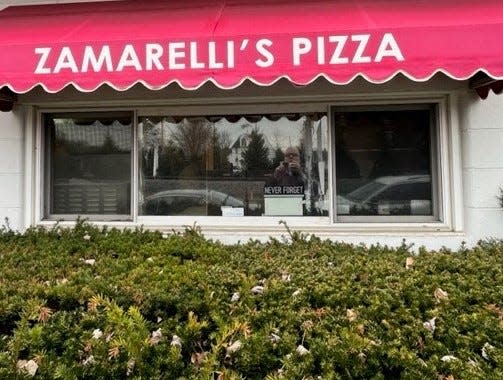 A sign in the window of Zamarelli's Pizza Palace shows support for U.S. troops with the saying, "Never Forget."