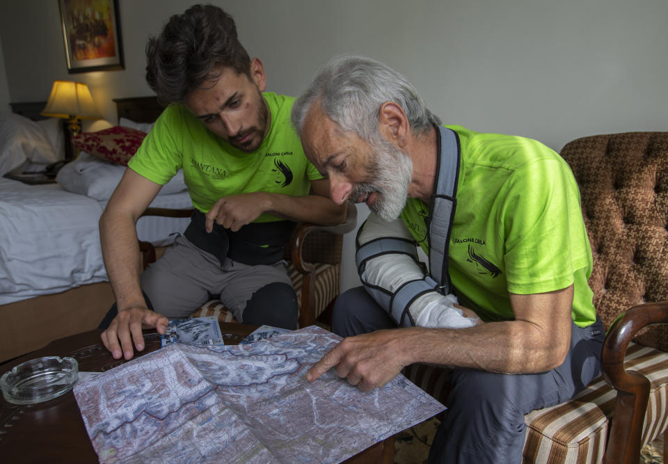 The team leader, Tarcisio Bellò, 57, right, shows the site of avalanche to his team member Luca Morellato in Islamabad, Pakistan, Thursday, June 20, 2019. The renowned Italian mountaineer, who narrowly survived along-with six other members of an expedition on a mountain, burst into tears Thursday when he recalled how helplessly he saw one of his Pakistani colleagues being swept away by an avalanche that struck them at an altitude of around 5,300 meters (17,390 feet) earlier this week. (AP Photo/B.K. Bangash)