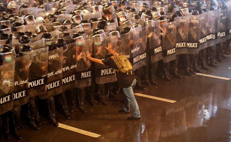 A man pushes against police officers during an anti-government protest, in Bangkok