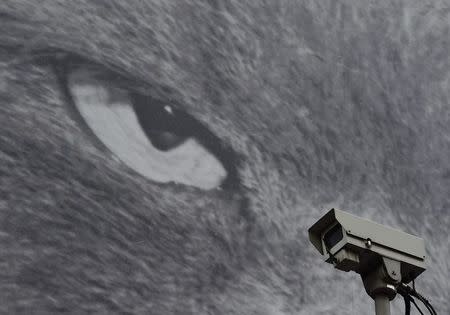 A CCTV camera is seen in front of a large poster opposite a London Underground Station in central London, November 24, 2014. REUTERS/Toby Melville