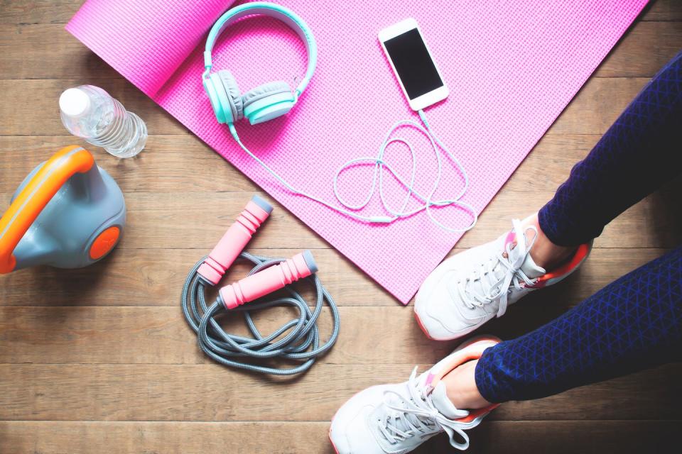 overhead shot of a woman sat on an exercise mat with headphones and dumbbells